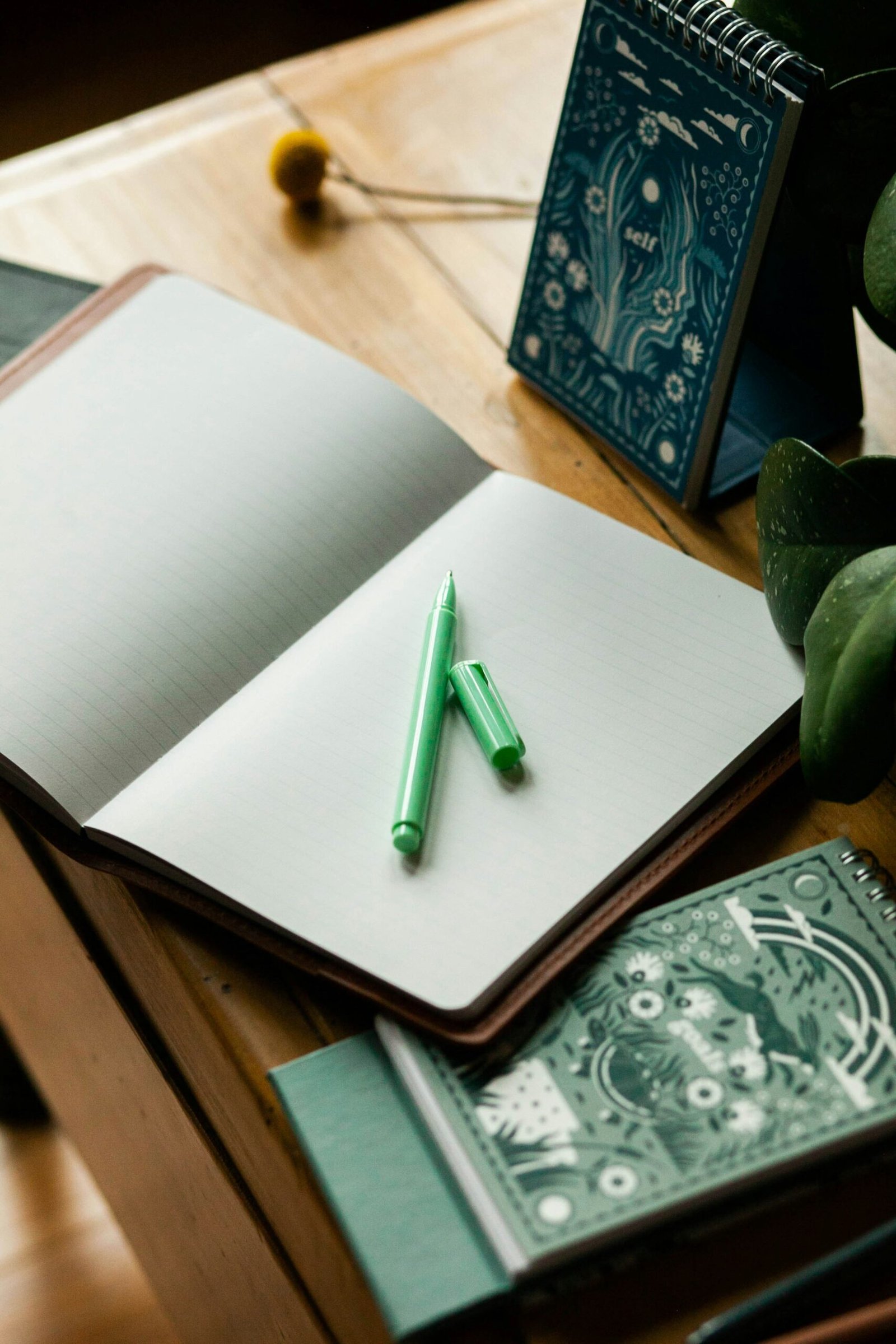 a notebook with a green pen on top of it to journal for anxeity